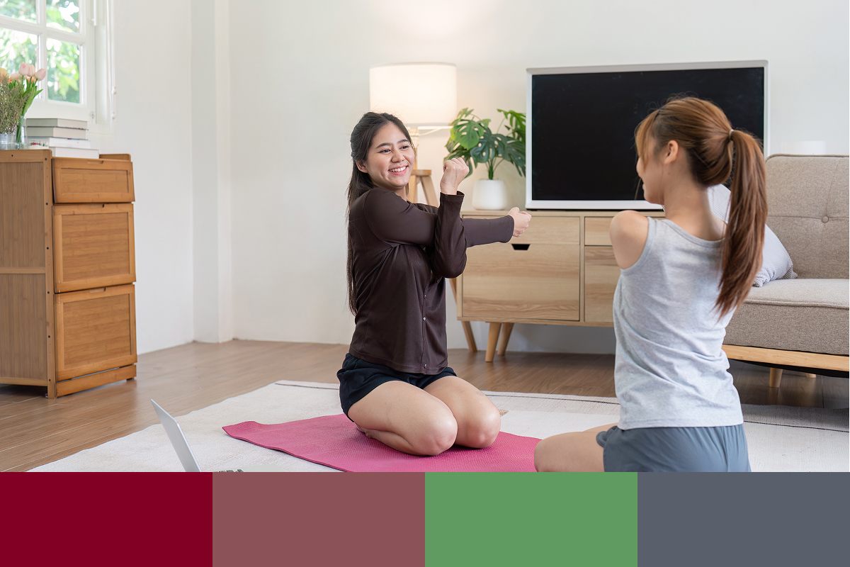Two women stretching together on yoga mats in a cozy living room during an at-home wellness session — guided by Pattison Health.
